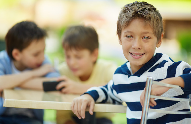 Portrait of smiling boy in cafe with his friends in the background