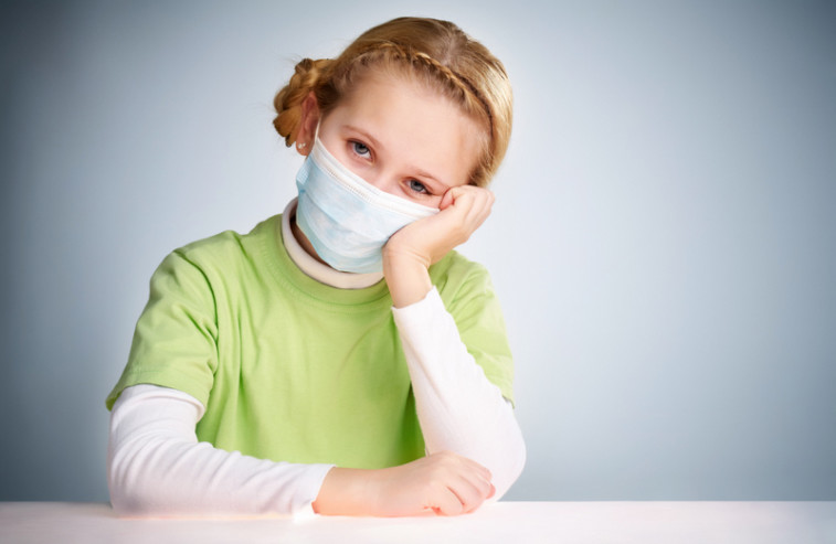 A little girl sitting in protective mask